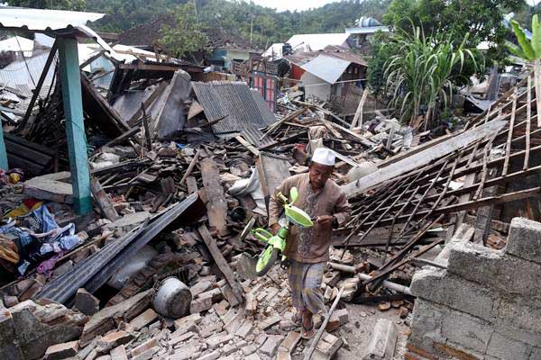Warga mengangkat sepeda dari reruntuhan rumah yang rusak akibat gempa bumi di Lombok Barat, NTB, Senin (6/8/2018). Gempa bumi megathrust, disebut sebagai gempa terbesar di dunia - ANTARA/Zabur Karuru