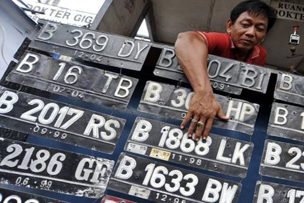 Seorang tukang plat nomor polisi (nopol) merapikan deretan plat nomor registrasi kendaraan bermotor, di kawasan Jatinegara, Jakarta Timur - Antara
