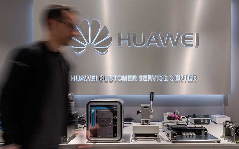 Karyawan melintas di dekat logo Huawei Technologies Co. di pusat layanan di Brussels, Belgia, Selasa (4/2/2020). Bloomberg - Geert Vanden Wijngaert