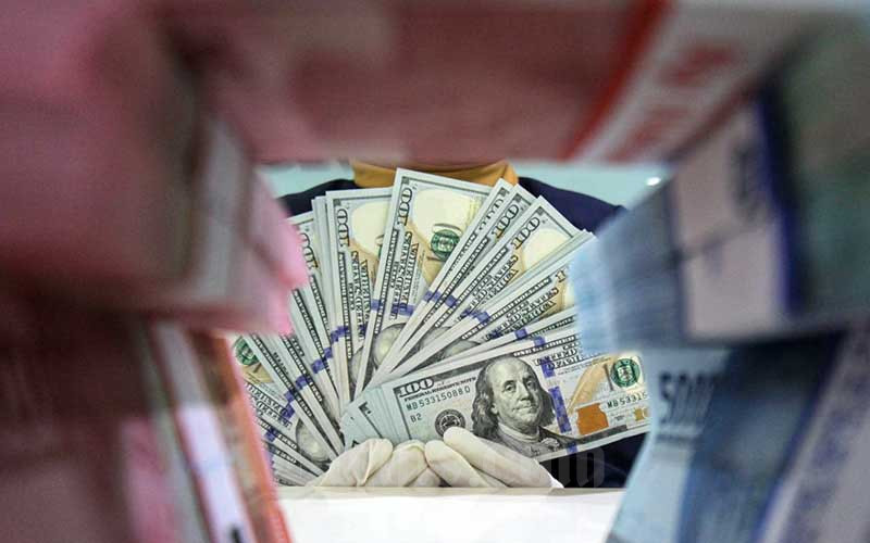 Karyawati salah satu bank memperlihatkan uang rupiah dan dolar di Jakarta, Kamis (29/4/2021). Bisnis - Arief Hermawan P