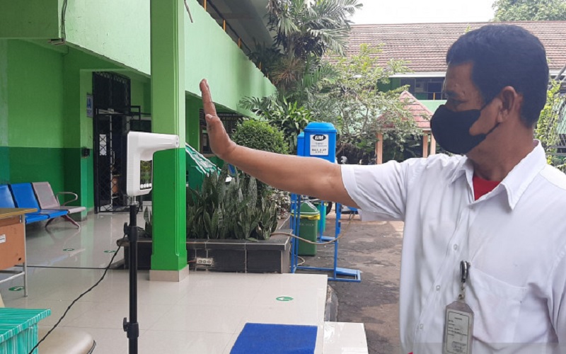 Salah satu tenaga kependidikan sedang memeriksa suhu tubuh sebelum memasuki ruangan sekolah pada saat PTM terbatas di SMA N 46 Jakarta, Rabu (15/9/2021). ANTARA - Sihol Hasugian