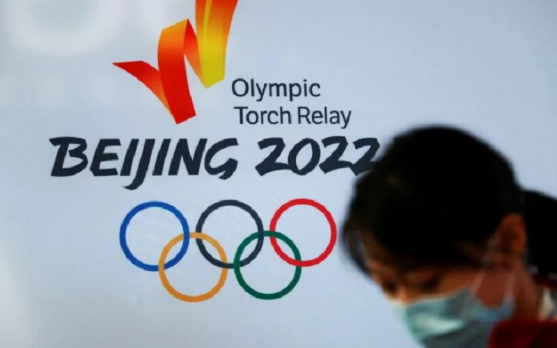 Seorang perempuan melintas di dekat logo Olimpiade Musim Dingin 2022 Beijing saat tur obor di Universitas Telekomunikasi dan Pos Beijing, Beijing, China, Kamis (9/12/2021). - Antara/Reuters