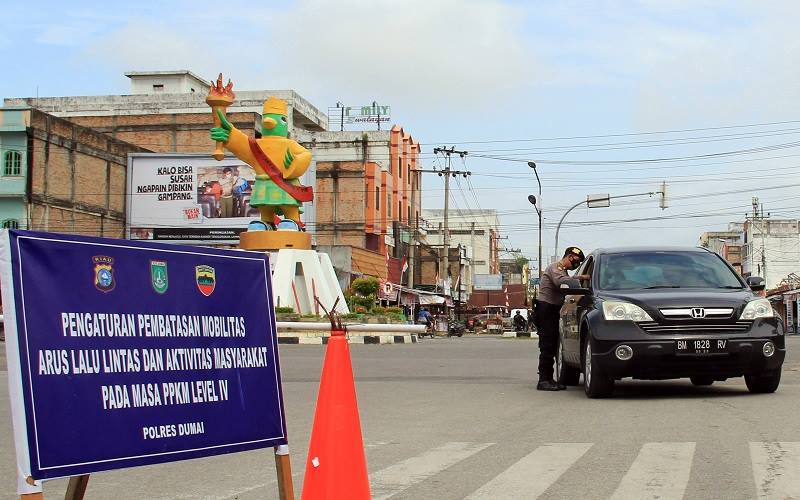 Anggota polisi memeriksa kendaraan yang akan melintas di lokasi penyekatan Pemberlakuan Pembatasan Kegiatan Masyarakat (PPKM) Level IV di Dumai, Riau, Sabtu (14/8/2021). Penyekatan PPKM Level IV di Dumai berlaku hingga 23 Agustus 2021 untuk mencegah penyebaran wabah COVID-19 di daerah tersebut yang jumlah kasus harian sebanyak 64 orang dan jumlah kematian sebanyak 20 orang per minggu. ANTARA FOTO - Aswaddy Hamid