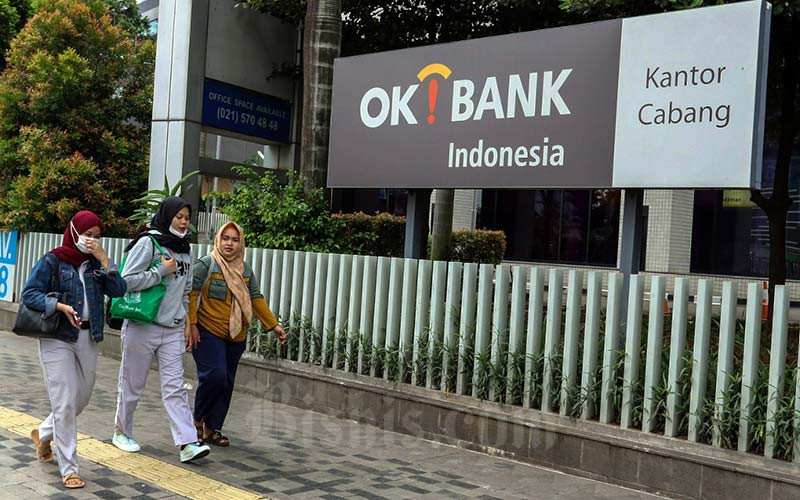 Warga melintasi logo PT Bank Oke Indonesia Tbk. (DNAR) di Jakarta.  - Bisnis/Eusebio Chrysnamurt