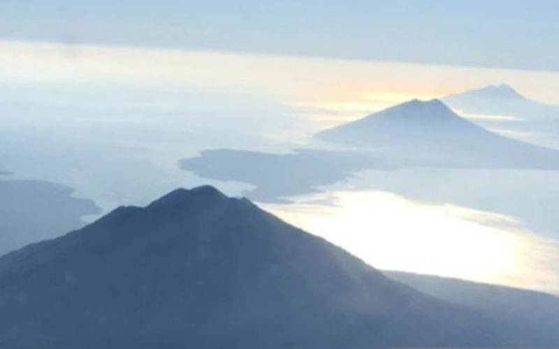 Gunung Ili Lewotolok (tengah) di Lembata berderet dengan Gunung Ile Boleng (depan) di Pulau Adonara, Flores Timur, NTT. Foto dari udara. - Antara/Bernadus Tokan