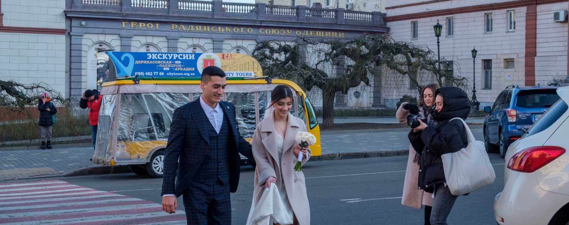 Pejalan kaki mengambil foto pasangan yang baru menikah menyeberang jalan di Odessa, Ukraina, pada Sabtu (22/1/2022). - Bloomberg/Christopher Occhicone