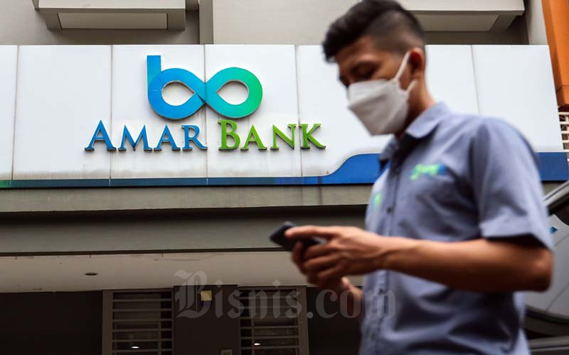 Warga beraktivitas dengan latar logo PT Bank Amar Indonesia Tbk. (AMAR) di Jakarta, Selasa (25/1/2022). Bisnis - Eusebio Chrysnamurti