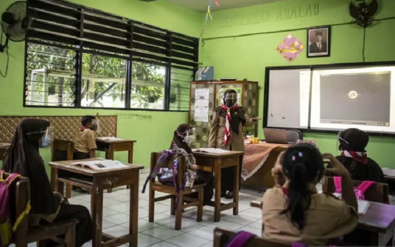 Guru (tengah) memberikan materi pelajaran kepada murid saat uji coba pembelajaran tatap muka pada hari pertama di SD Negeri Kenari 08 Pagi, Jakarta, Rabu (7/4/2021). - Antara