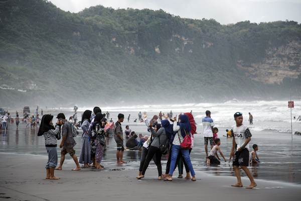 Pengunjung menikmati suasana Pantai Parangtritis, Bantul, DI Yogyakarta, Selasa (25/12/2018). - ANTARA FOTO/Hendra Nurdiyansyah