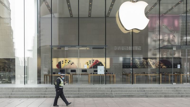 Seorang petugas polisi yang mengenakan masker pelindung berjalan melewati toko Apple yang tutup di Shanghai, China, pada 5 Februari 2020. -  Qilai Shen / Bloomberg