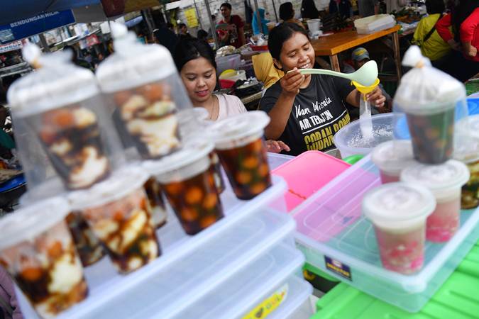 Pedagang membungkus minuman untuk dijual di Pasar Takjil Benhil, Jakarta, Senin (6/5/2019). - ANTARA/Sigid Kurniawan