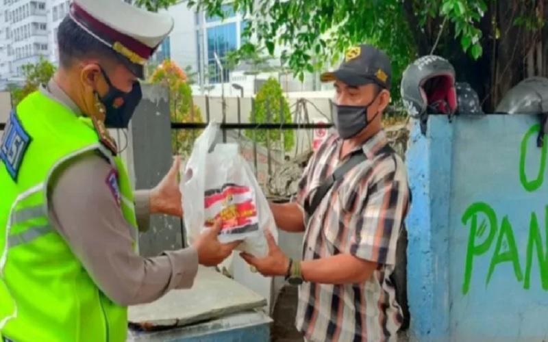 Petugas kepolisian menyerahkan bantuan sosial berupa beras kepada warga di wilayah Jakarta Barat, Sabtu (10/7/2021). - Antara