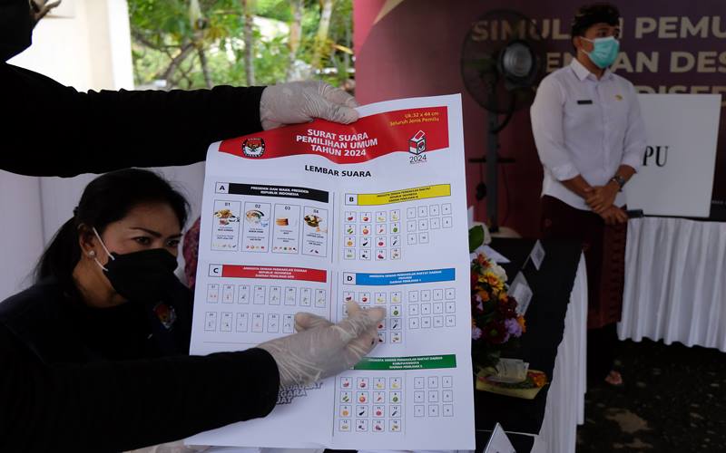Anggota KPPS menunjukkan surat suara kepada pemilih saat simulasi pemungutan dan penghitungan suara dengan desain surat suara dan formulir yang disederhanakan dalam persiapan penyelenggaraan Pemilu serentak tahun 2024 di Kantor KPU Provinsi Bali, Denpasar, Bali, Kamis (2/12/2021).  - Bisnis