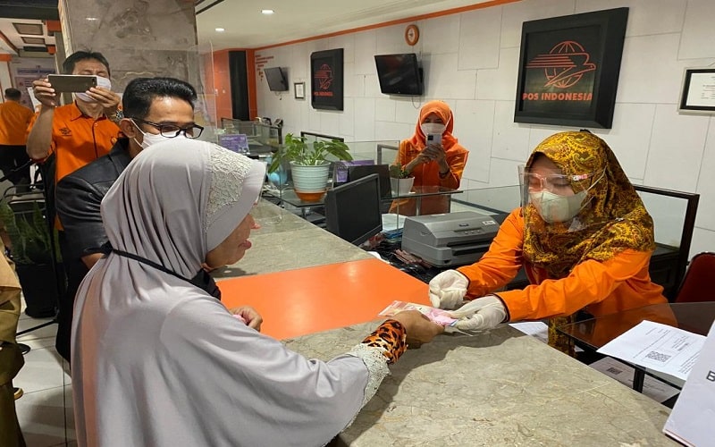 Petugas PT Pos Indonesia menyerahkan bantuan langsung tunai (BLT) minyak goreng dan sembako kepada salah seorang warga di Kota Balikpapan. - Istimewa 