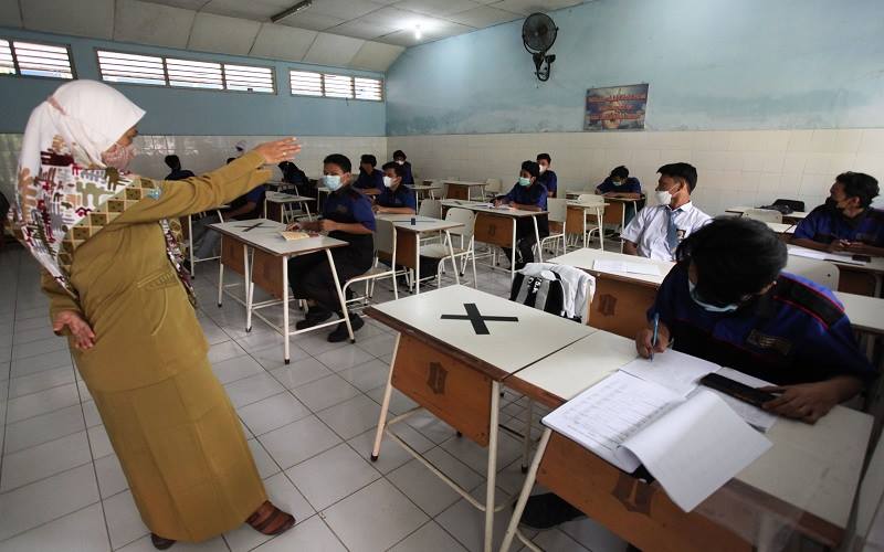 Guru mengajar muridnya di ruang kelas di SMK Negeri 7 Surabaya, Jawa Timur, Senin (30/8/2021). Pemprov Jawa Timur memulai pembelajaran tatap muka (PTM) secara terbatas di 2.536 SMA/SMK dan SLB di 20 kabupaten/kota di Jawa Timur yang telah menerapkan PPKM Level 2 dan 3, sedangkan di wilayah PPKM level 4 kegiatan PTM secara terbatas belum digelar. ANTARA FOTO - Didik Suhartono