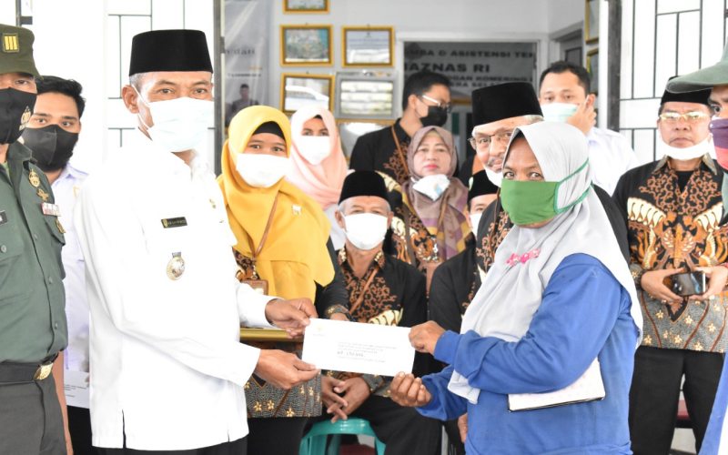 Wakil Bupati Kabupaten OKI M. Dja'far Shodiq (kanan) menyerahkan zakat kepada petugas kebersihan di kabupaten tersebut.  - Istimewa