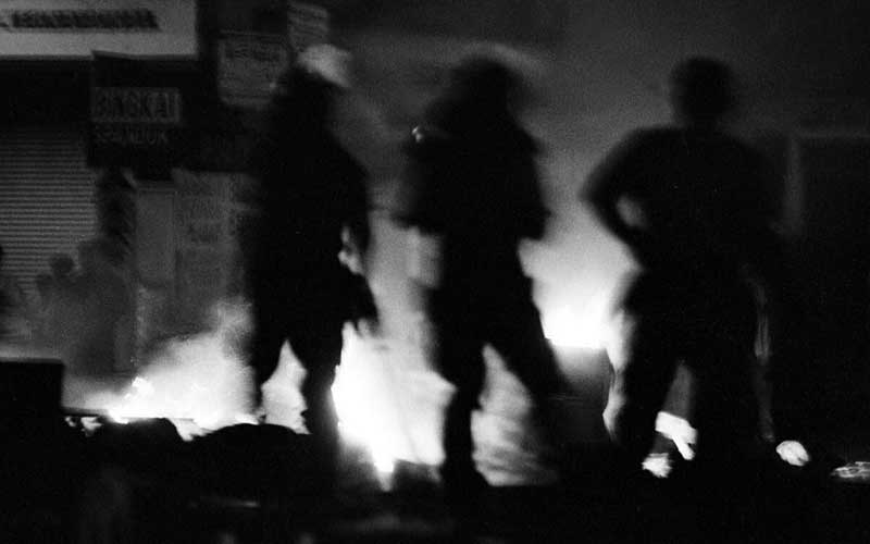 FOTO ARSIP - Tiga petugas kepolisian berjaga-jaga di dekat sebuah mobil yang terbakar dalam kerusuhan di kawasan pertokoan Bendungan Hilir, Jakarta, (13/5/1998). Aksi kerusuhan dan penjarahan mulai terjadi di beberapa wilayah Ibu Kota menyusul tewasnya empat mahasiswa Universitas Trisakti. ANTARA FOTO/Mosista Pambudi - aww.\n