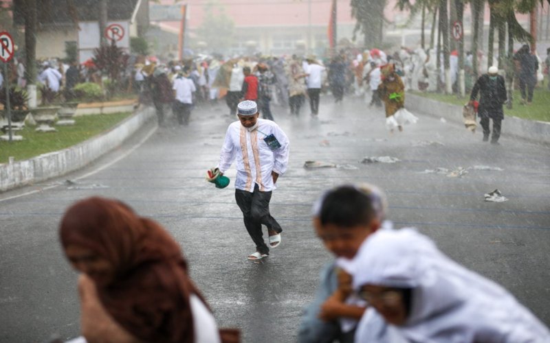 Para jemaah berlarian di tengah hujan deras di halaman Kantor Gubernur Sumatra Barat.  - Tim Jelajah Lebaran 2022. 