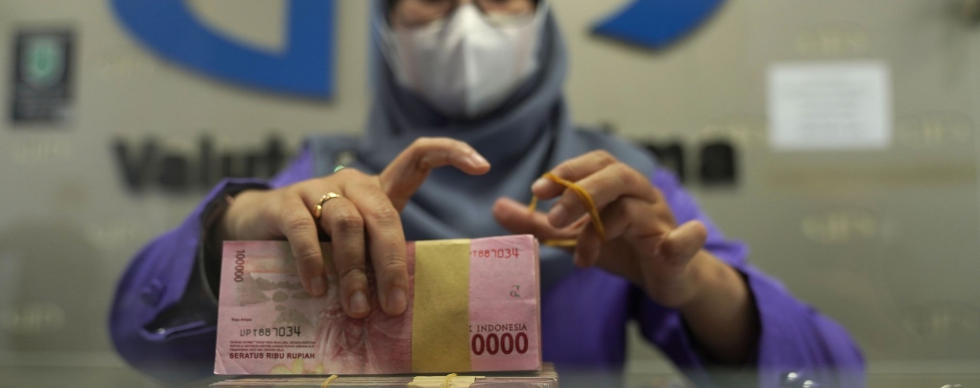 Seorang pekerja mengatur bundel uang kertas Rp100.000 di kantor penukaran mata uang di Jakarta, Rabu, (2/3/2022). Bloomberg - Dimas Ardian