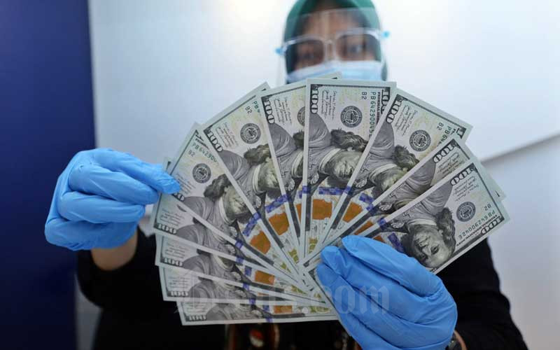 Karyawan menunjukan Dolar AS di Jakarta, Rabu (27/1/2021). Nilai tukar rupiah di pasar spot ditutup menguat 15 poin atau 0,11 persen menjadi Rp14.050 per dolar AS. Bisnis - Eusebio Chrysnamurti