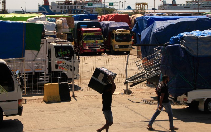 Sejumlah pria berjalan di antara truk pembawa logistik antarpulau di NTT di pelabuhan Angkutan Sungai, Danau dan Penyeberangan (ASDP) Indonesia Ferri di Bolok, Kupang, NTT (4/6/2020). Sebanyak 30 truk pengangkut logistik dan sembako ke sejumlah pulau di NTT tertahan di pelabuhan tersebut akibat pembatasan 50 persen kapasitas angkutan kapal guna mencegah penyebaran Covid-19.  - ANTARA