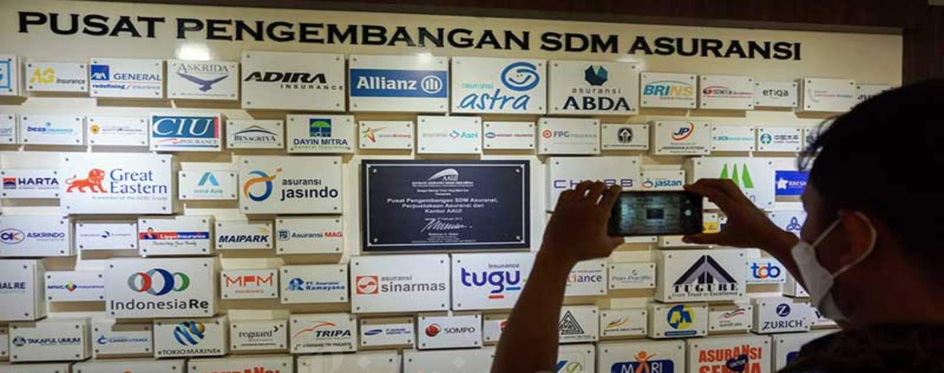 Karyawan beraktivitas di dekat logo-logo perusahaan asuransi di kantor Asosiasi Asuransi Umum Indonesia (AAUI) di Jakarta, Rabu (5/1/2021). Bisnis - Suselo Jati