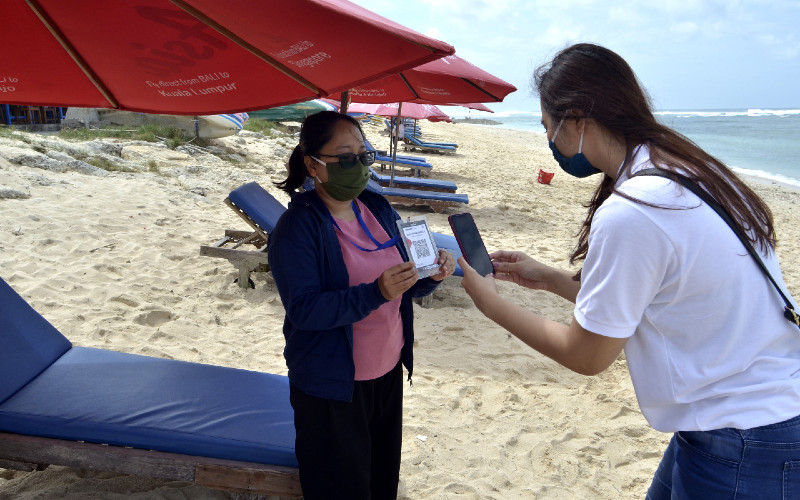 Pengunjung melakukan transaksi pembayaran berbasis digital dengan pedagang pantai menggunakan Quick Response Code Indonesian Standard (QRIS) di Pantai Pandawa, Badung, Bali, Sabtu (11/7/2020). - ANTARA