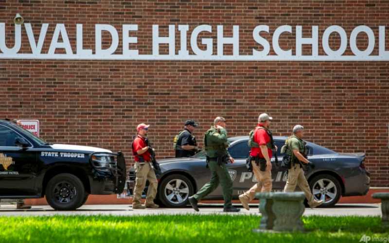Polisi berjalan di luar Uvalde High School setelah penembakan dilaporkan terjadi di Robb Elementary School, di Texas  -  William Luther The San Antonio Express / News via AP