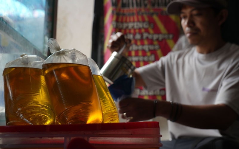 Seorang penjaga toko mengemas minyak goreng di Pasar Kambing, Jakarta, Indonesia, Kamis, (26/4 - 2022). Bloomberg / Dimas Ardian