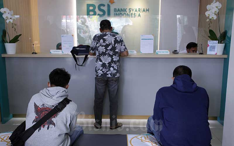 Karyawan melanyani nasabahyang melakukan transaksi di PT Bank Syariah Indonesia KC Jakarta Barat, Kebon Jeruk, Jakarta, Senin (1/2/2021).  - Bisnis