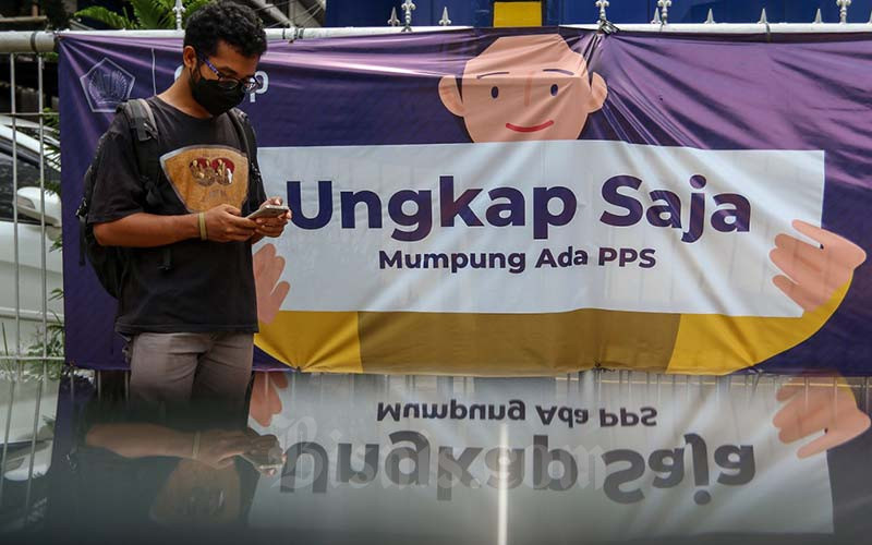 Warga melintasi spanduk Program Pengungkapan Sukarela (PPS) di salah satu kantor pelayanan pajak pratama di Jakarta, Senin (17/1/2022). Bisnis - Eusebio Chrysnamurti