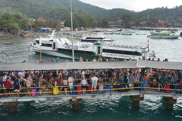 Sejumlah wisatawan calon penumpang menunggu jadwal keberangkatan kapal feri melalui Dermaga 2 Pelabuhan Padangbai, Karangasem, Bali, Jumat (20/7/2018). - ANTARA/Wira Suryantala