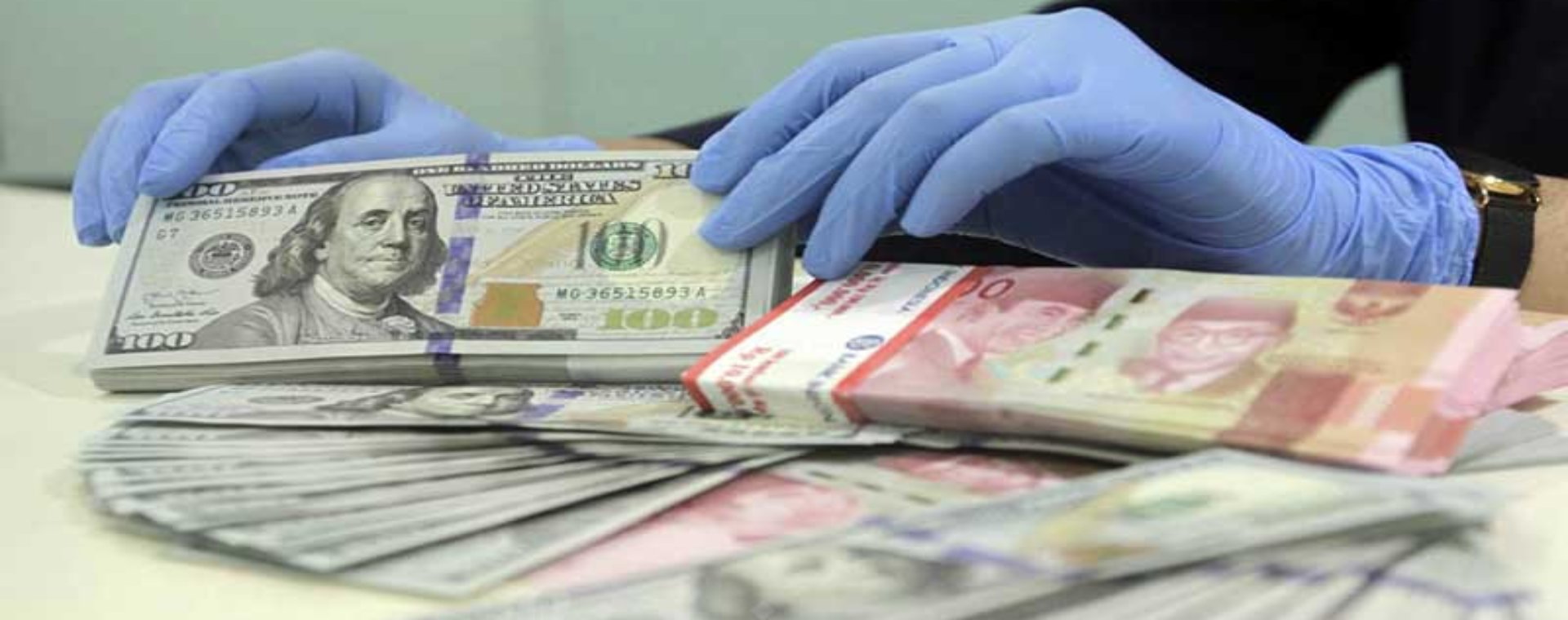 Karyawan merapikan uang dolar dan rupiah di salah satu bank di Jakarta, Kamis (14/1/2021). Bisnis - Himawan L Nugraha