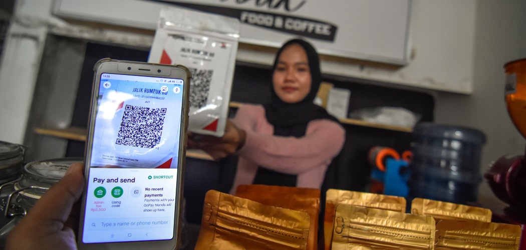 Seorang warga menggunakan pembayaran nontunai Quick Response Indonesia Standard (QRIS) saat membeli kopi di warung kopi Jalik Rumbuk di Mataram, NTB, Selasa (12/1/2021). - ANTARA FOTO/Ahmad Subaidi. Intip Persaingan ARTO, BBSI, BBYB, BANK, dkk di Segmen UMKM