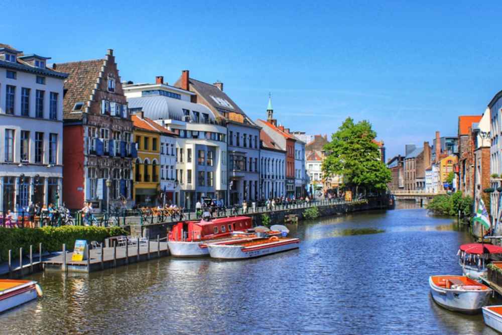 Wisata air sepanjang saluran air Ghent dengan pemandangan distrik kota tua abad pertengahan kota, melewati fasad guidhall, pelabuhan abad pertengahan, serta gereja di Ghent.
