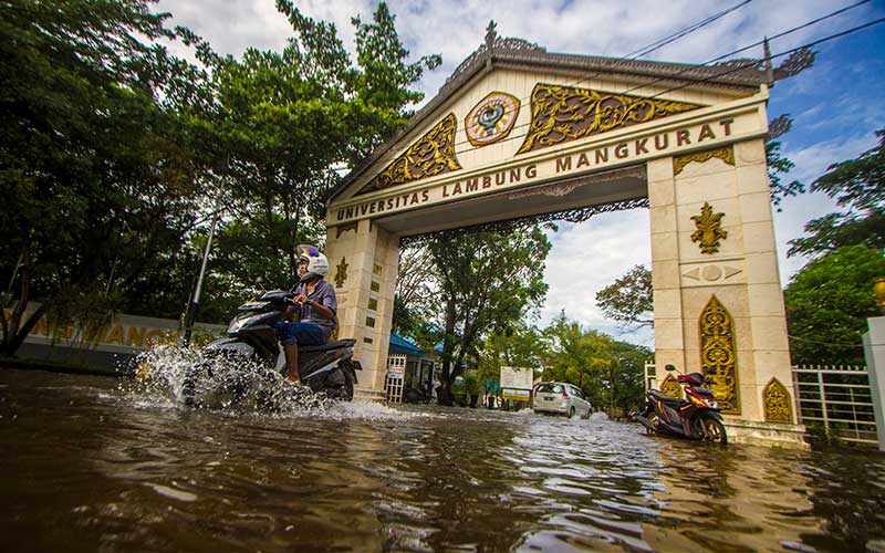 Pengendara motor menorobos banjir yang menggenangi jalan masuk ke Universitas Lambung Mangkurat di Banjarmasin, Kalimantan Selatan, Rabu (8/12/2021). Sejumlah daerah di daerah tersebut tergenang banjir dan Pemprov. Kalsel menetapkan status tanggap darurat bencana banjir, tanah longsor, angin puting beliung dan gelombang pasang di provinsi Kalimantan Selatan dari 03 Desember 2021 hingga 16 Desember 2021 akibat semakin tingginya curah hujan. ANTARA FOTO/Bayu Pratama S