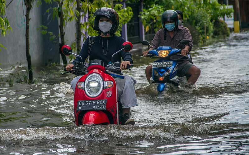 Pengendara motor menorobos banjir yang menggenangi jalan masuk ke Universitas Lambung Mangkurat di Banjarmasin, Kalimantan Selatan, Rabu (8/12/2021). Sejumlah daerah di daerah tersebut tergenang banjir dan Pemprov. Kalsel menetapkan status tanggap darurat bencana banjir, tanah longsor, angin puting beliung dan gelombang pasang di provinsi Kalimantan Selatan dari 03 Desember 2021 hingga 16 Desember 2021 akibat semakin tingginya curah hujan. ANTARA FOTO/Bayu Pratama S