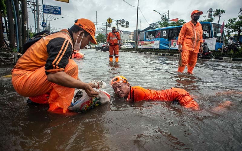 Petugas PPSU membersihkan sampah yang menyumbat saluran air saat banjir di Jalan Gunung Sahari, Mangga Dua, Jakarta, Selasa (18/1/2022). Banjir tersebut terjadi karena buruknya drainase di kawasan itu serta tingginya instensitas hujan pada Selasa (18/1) siang. ANTARA FOTO/Aprillio Akbar