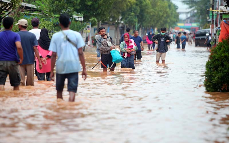 Warga melintasi banjir di Desa Kedawung, Grati, Pasuruan, Jawa Timur, Selasa (18/1/2022). Hujan deras dengan intensitas tinggi tersebut mengakibatkan belasan desa di tiga kecamatan wilayah timur Kabupaten Pasuruan terendam banjir dengan ketinggian hingga satu meter. ANTARA FOTO/Umarul Faruq