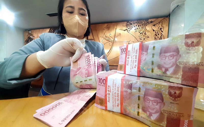 Karyawan menghitung uang rupiah di salah satu bank di Jakarta, Rabu (19/1/2022). Rupiah ditutup melemah 0,08 persen atau 12 poin ke Rp14.336 per dolar AS.  Sementara itu, indeks dolar AS yang mengukur kekuatan greenback menguat 0,05 persen atau 0,04 poin ke 95,31. Bisnis/Himawan L Nugraha