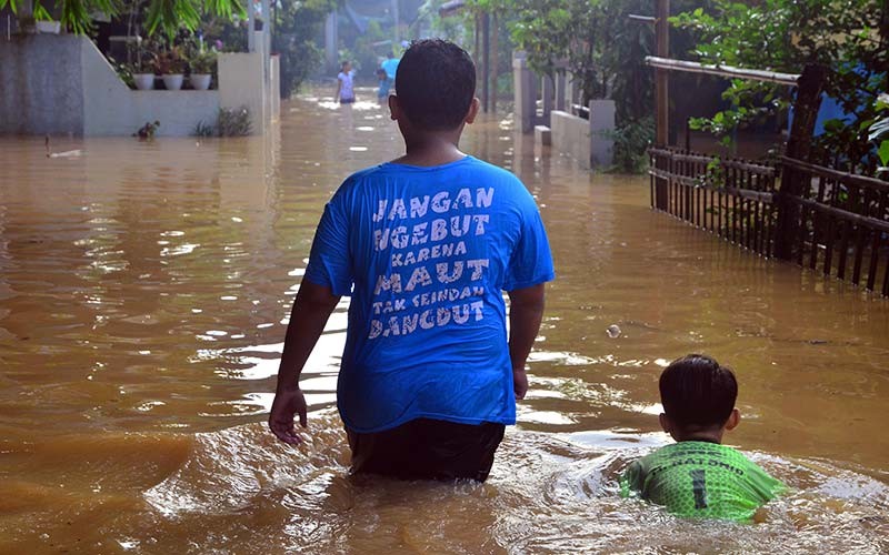 Dua anak melintasi jalan yang tergenang banjir di Desa Golantepus, Mejobo, Kudus, Jawa Tengah, Kamis (20/1/2022). Akibat intensitas hujan yang tinggi serta meluapnya Sungai Mrisen menyebabkan ratusan rumah dan jalan utama di desa itu terendam banjir. ANTARA FOTO/Yusuf Nugroho