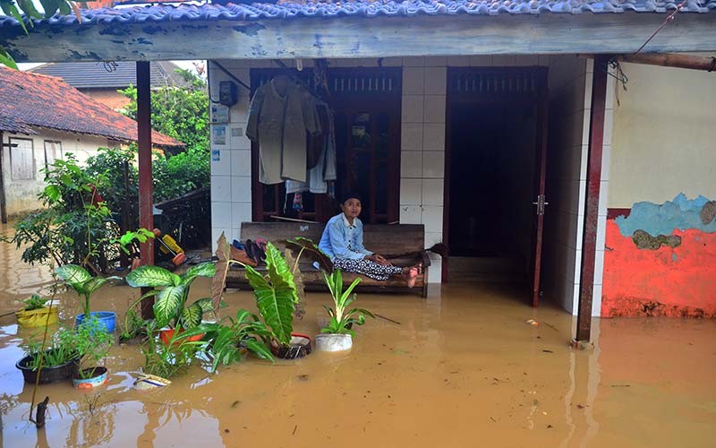 Warga duduk di teras rumah yang tergenang banjir di Desa Golantepus, Mejobo, Kudus, Jawa Tengah, Kamis (20/1/2022). Akibat intensitas hujan yang tinggi serta meluapnya Sungai Mrisen menyebabkan ratusan rumah dan jalan utama di desa itu terendam banjir. ANTARA FOTO/Yusuf Nugroho