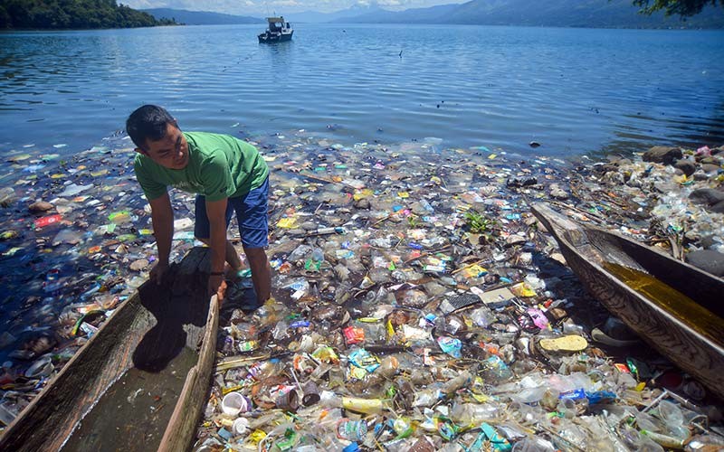 Warga memindahkan biduk di antara sampah di tepian Danau Singkarak, Nagari Sumpu, Kabupaten Tanah Datar, Sumatera Barat, Kamis (20/1/2022). Tepian danau wisata tersebut dipenuhi sampah plastik sejak sepekan terakhir yang menyulitkan nelayan mencari ikan. ANTARA FOTO/Iggoy el Fitra