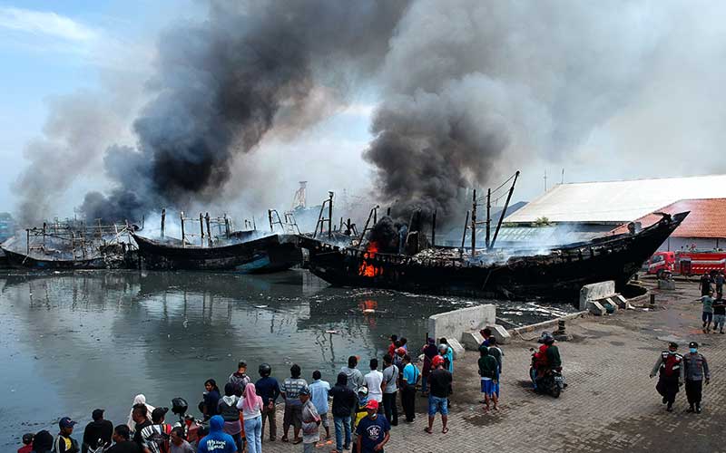 Petugas pemadam kebakaran menyemprotkan air pada kapal nelayan yang terbakar di Pelabuhan Tegal, Jawa Tengah, Sabtu (29/1/2022). Sebanyak 13 kapal nelayan yang akan melaut terbakar sekitar pukul 04.30 WIB dan pihak terkait masih menyelidiki penyebab musibah tersebut. ANTARA FOTO/Oky Lukmansyah