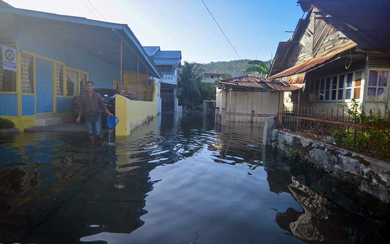 Seorang warga mengumpulkan sampah di depan rumahnya saat banjir rob menggenangi kawasan Berok Nipah, Kota Padang, Sumatera Barat, Rabu (18/5/2022). Banjir rob menggenangi permukiman penduduk di sejumlah titik di kota Padang sejak tiga hari terakhir. ANTARA FOTO/Iggoy el Fitra