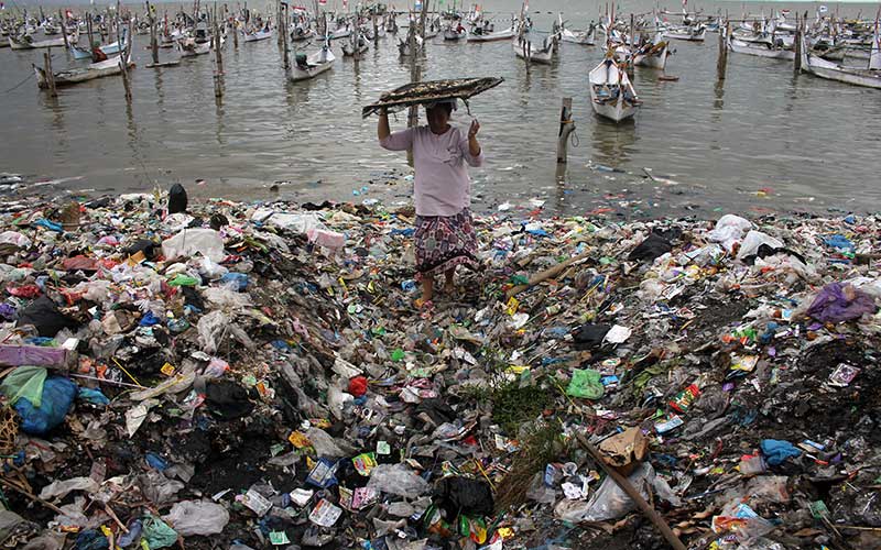 Warga membawa ikan di pantai yang penuh dengan sampah plastik di Desa Kwanyar Barat, Bangkalan, Jawa Timur, Sabtu (21/5/2022). Sampah rumah tangga yang mencemari pesisir pantai di kawasan tersebut akibat kurangnya kesadaran masyarakat menjaga kebersihan lingkungan serta minimnya tempat pembuangan akhir (TPA) sehingga berdampak pada keberlangsungan ekosistem laut. ANTARA FOTO/Patrik Cahyo Lumintu