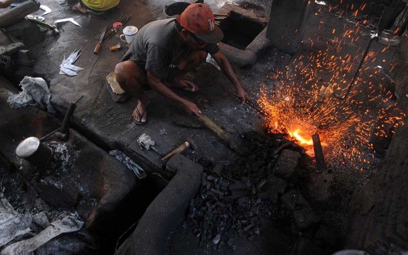 Perajin pandai besi tradisional membakar bahan besi dan baja saat membuat arit di Segaran, Delanggu, Klaten, Jawa Tengah, Selasa (5/7/2022). Menurut perajin setempat, keberlangsungan pandai besi saat ini masih minim regenerasi sehingga jumlah pelaku perajin pandai besi tradisional pembuat arit, golok, dan pisau makin menurun. ANTARA FOTO/Aloysius Jarot Nugroho