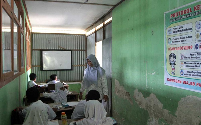 Sejumlah siswa mengikuti pembelajaran di lorong sekolah yang diubah menjadi ruang kelas di SDN Karangmalang 1, Ngawi, Jawa Timur, Selasa (9/8/2022). Akibat rusaknya bangunan di sekolah tersebut sekitar 35 siswa dari tiga kelas terpaksa mengikuti pelajaran di lorong sekolah dan berbagi ruangan. ANTARA FOTO/Ari Bowo Sucipto