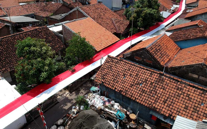 Foto udara bendera merah putih terpanjang di Desa Pekauman Kulon, Kabupaten Tegal, Jawa Tengah, Senin (15/8/2022). Bendera sepanjang 150 meter yang dijahit selama lima hari tersebut dipasang dalam rangka menyambut HUT ke 77 Kemerdekaan RI. ANTARA FOTO/Oky Lukmansyah
