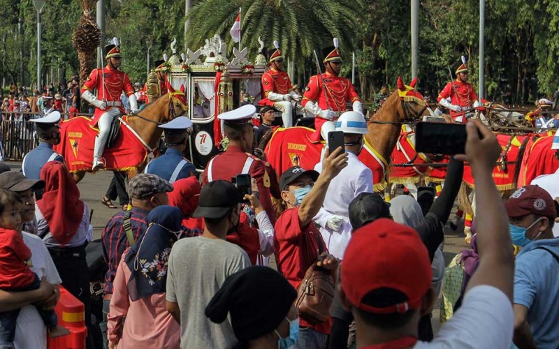 Warga menyaksikan Kirab Bendera Pusaka Merah Putih di Lapangan Silang Monumen Nasional, Jakarta, Rabu (17/8/2022). Kirab Bendera Pusaka tersebut menjadi salah satu rangkaian dalam upacara Hari Ulang Tahun Kemerdekaan ke-77 Republik Indonesia. Bisnis/Fanny Kusumawardhani